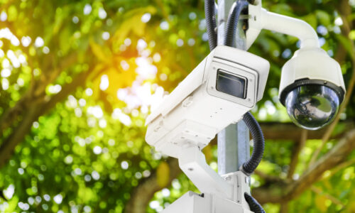 Modern public CCTV camera on a electric pole with blurred natural background. Intelligent reccording cameras for monitoring all day and night. Concept of surveillance and monitoring with copy space.